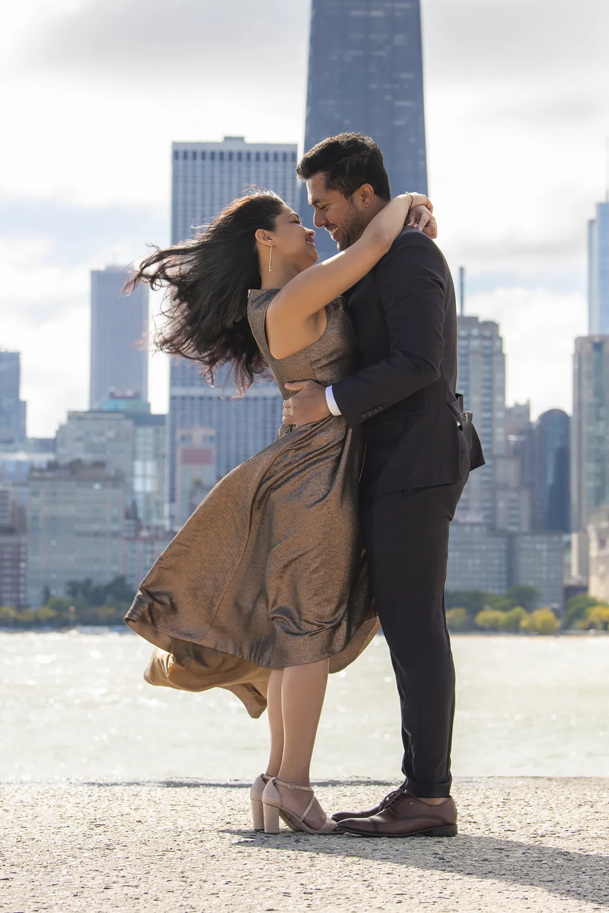 Couple embracing by the lake with the Chicago skyline behind them